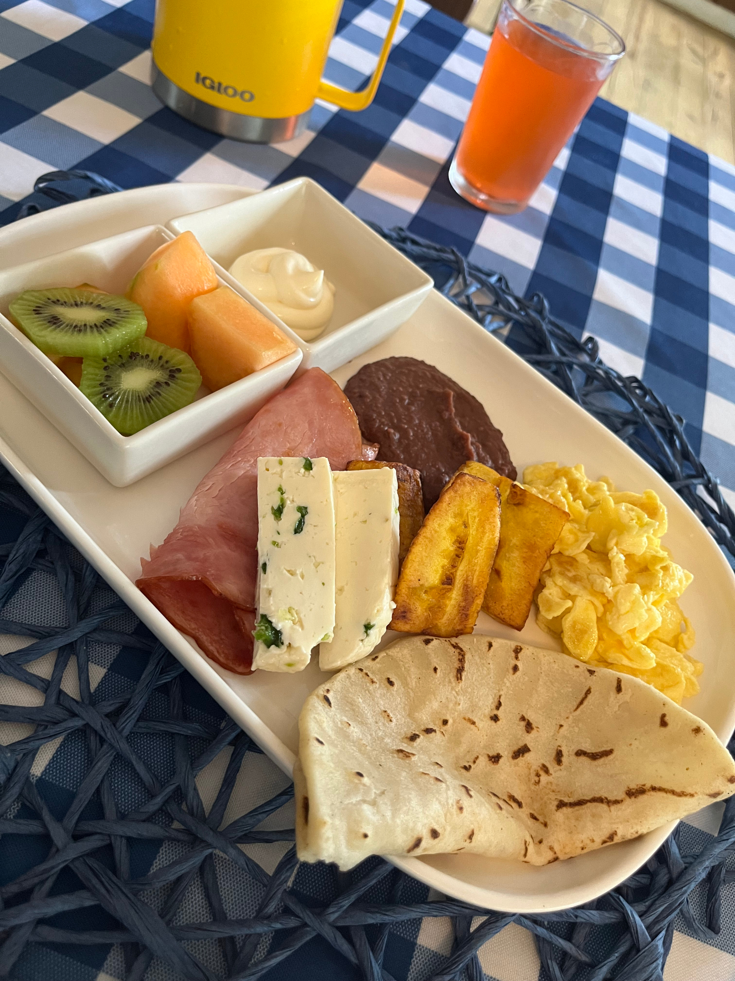 Tropical breakfast platter with kiwi, melon, ham, fresh cheese, fried plantains, scrambled eggs and a handmade flour tortilla